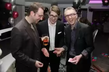 Close-up magician performing card tricks for guests at a party with balloons
