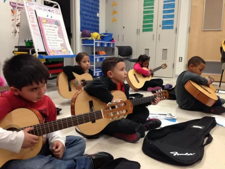 Children playing musical instruments together in a group lesson