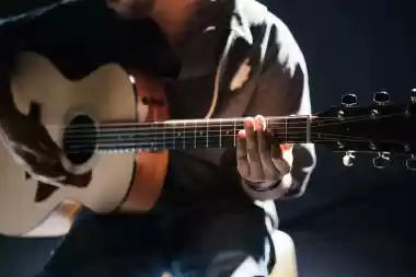 Guitarist playing acoustic guitar in a dark setting