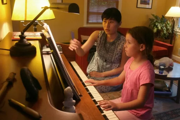 Piano teacher guiding a student during a lesson