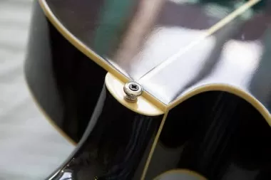 Close-up of a guitar strap button on a black guitar