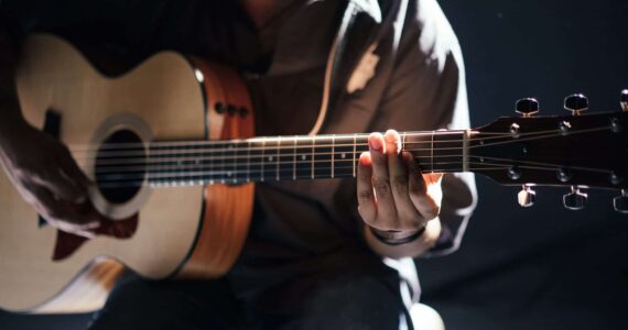 Guitarist playing acoustic guitar in a dark setting