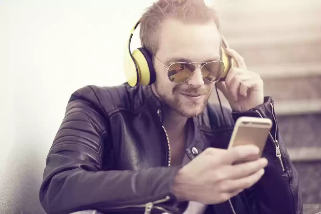 Musician wearing headphones and sunglasses using a mobile phone app