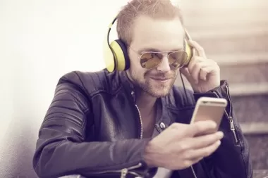 Musician wearing headphones and sunglasses using a mobile phone app