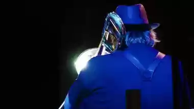 Musician with trombone seen from behind under blue stage lighting