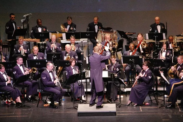 Military orchestra performing on stage with conductor