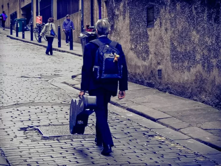Musician_walking_up_Niddry_Street_during_the_2014_Festival