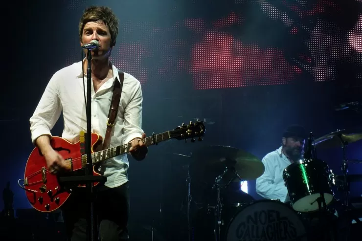 Noel Gallagher performing live on stage with guitar