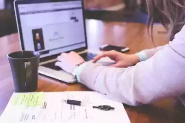 Person working on a laptop with notes and coffee on a desk