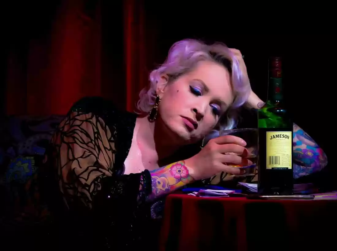 Singer resting with a glass of whiskey on stage