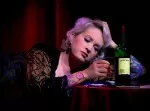 Singer resting with a glass of whiskey on stage
