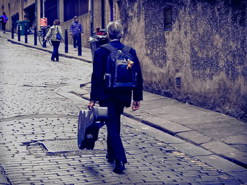 Musician_walking_up_Niddry_Street_during_the_2014_Festival